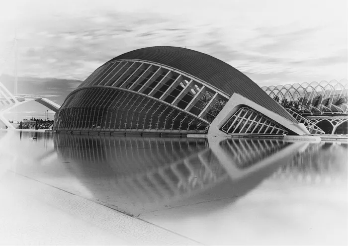 Hemisfèric van de Ciutat de les Arts i les Ciències in Valencia weerspiegelt als een groot oog in een ondiepe vijver, in lichte, bijna witte tonen.