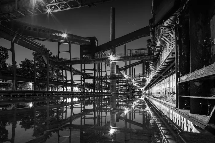 Stalen industriële constructies en een schoorsteen van Zollverein die 's nachts in stil water weerspiegelen