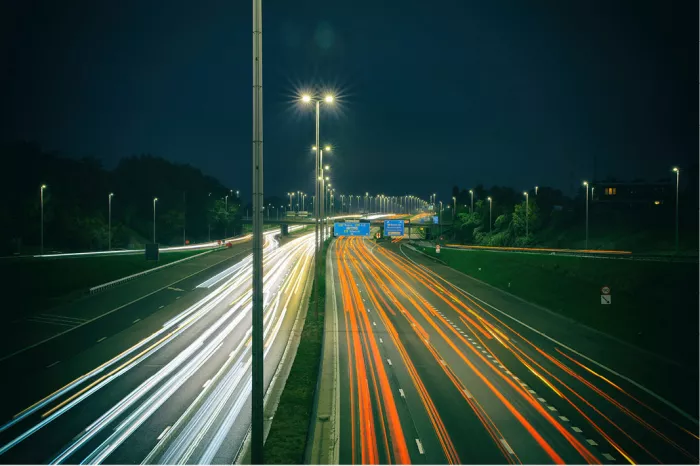 De A12 tijdens het spitsuur. Gefotografeerd tijdens het blauwe uurtje na zonsondergang. De lichtstrepen van de auto's geven de drukte weer op de autosnelweg. De verlichting geeft iets feeërieks aan de drukte.