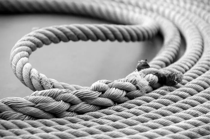 Close-up van opgerold scheepstouw in ronde lussen, met een gerafeld uiteinde