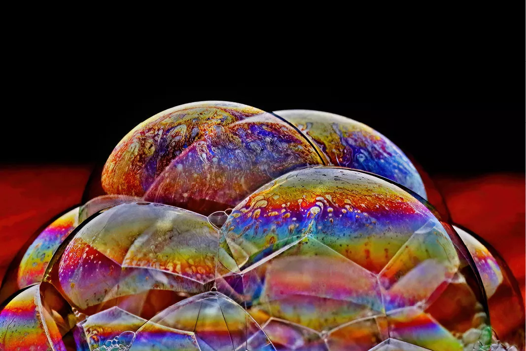 Tros zeepbellen met regenboogkleuren in het vlies tegen een zwarte achtergrond