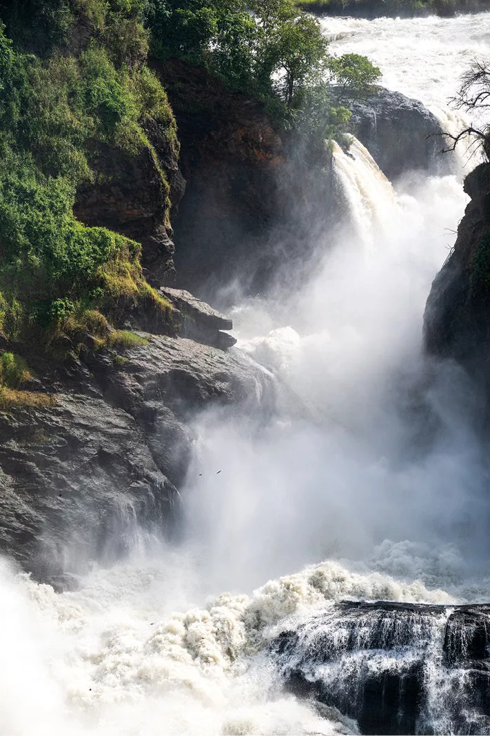 Wit schuimende waterval stort tussen donkere rotsen met groene begroeiing naar beneden
