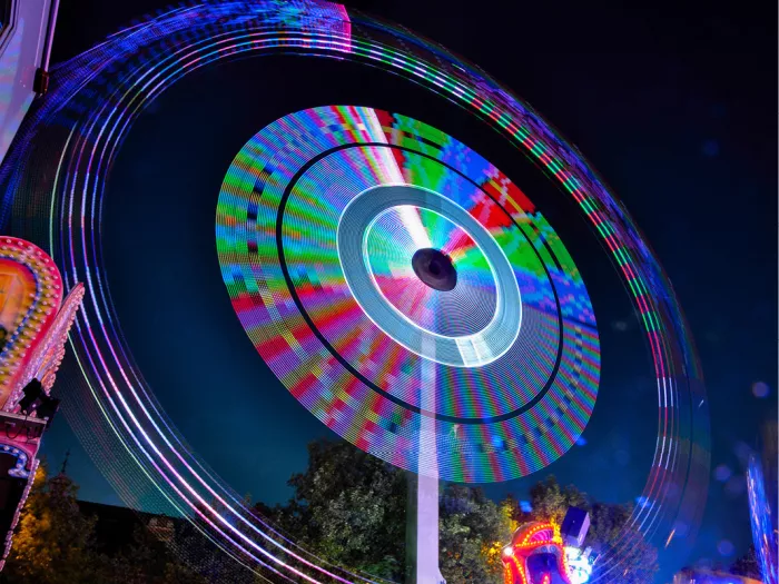 Draaiend reuzenrad bij nacht met kleurige lichtcirkels door lange sluitertijd