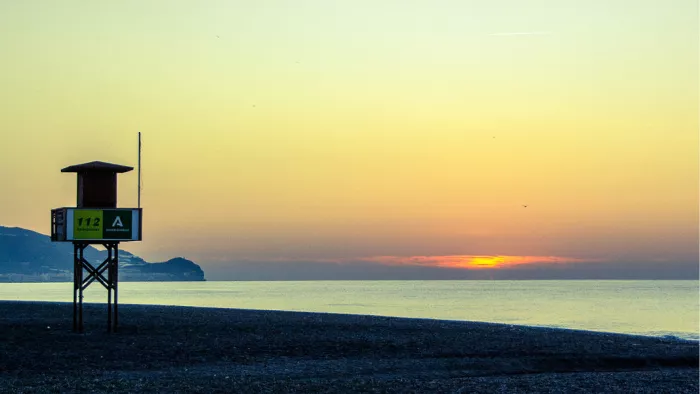 Reddingspost op hoge poten aan een kiezelstrand bij zonsondergang