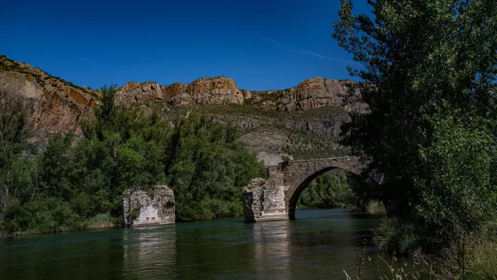 Oude stenen boogbrug met ingestorte pijlers in een rivier