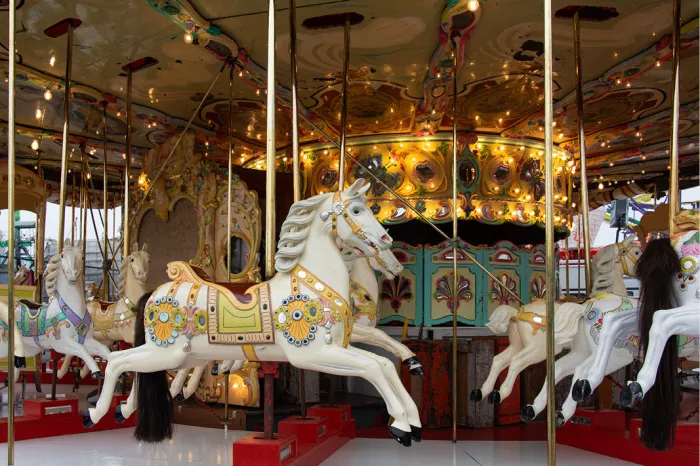 Wit carrouselpaard met beschilderde tuigage op een verlichte draaimolen
