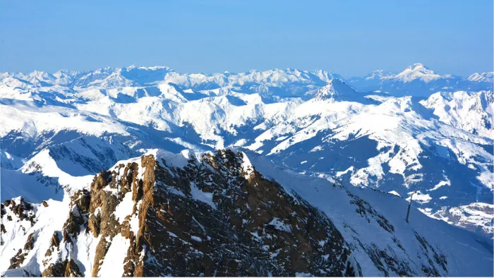Besneeuwde bergtoppen tot aan de horizon, met een rotsige graat op de voorgrond