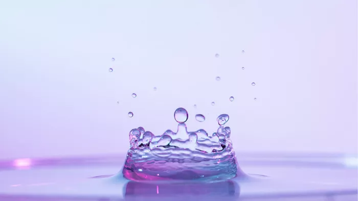 Waterdruppel die bij de impact opspat in de vorm van een kroon, in roze en lila tinten