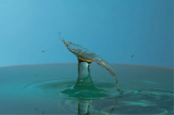Sikkelvormig gebogen waterscherm boven een waterzuil, in blauwe en groene tinten