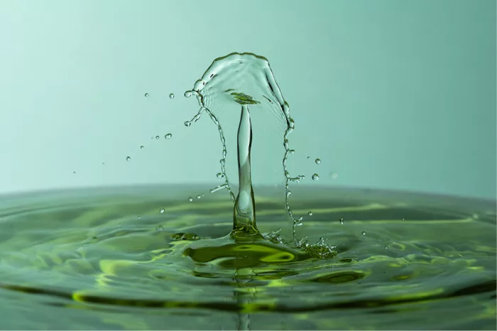 Hoge dunne waterzuil met een paraplu van water bovenaan, boven geelgroene kringen