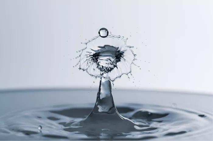 Klokvormig waterscherm op een zuil met een zwevende druppel erboven, in blauwgrijze tinten