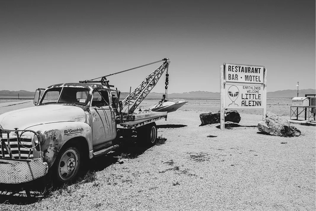 Oude takelwagen naast het bord van de Little A'Le'Inn in Rachel, Nevada, in zwart-wit
