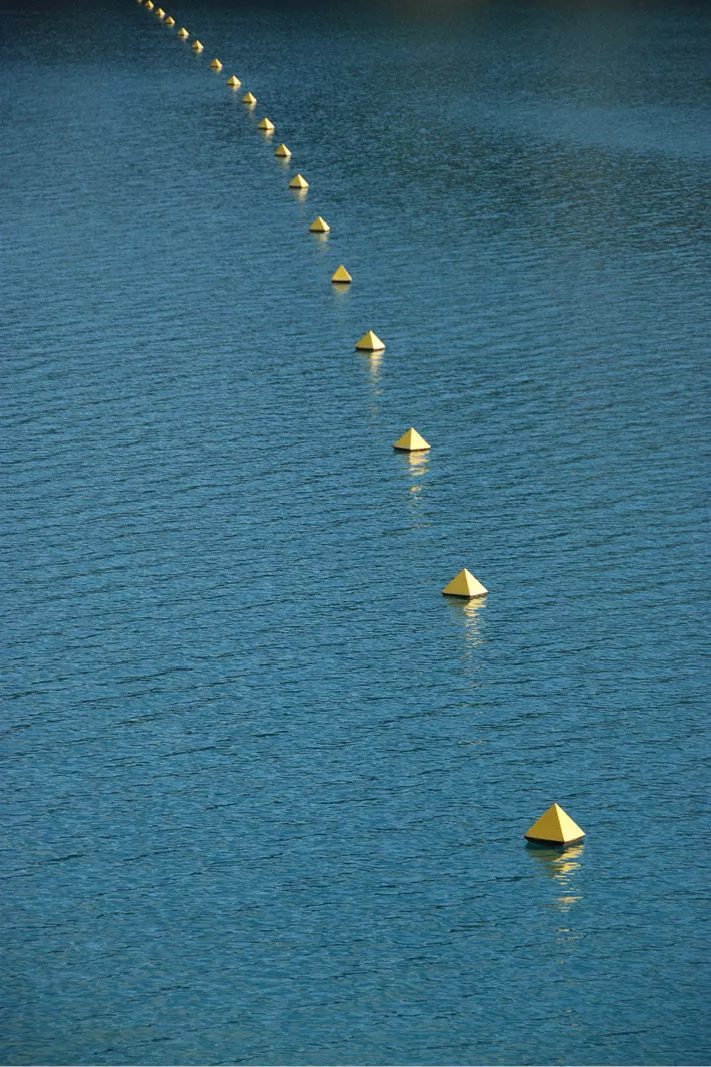 Rij gele boeien in een diagonale lijn over blauw water