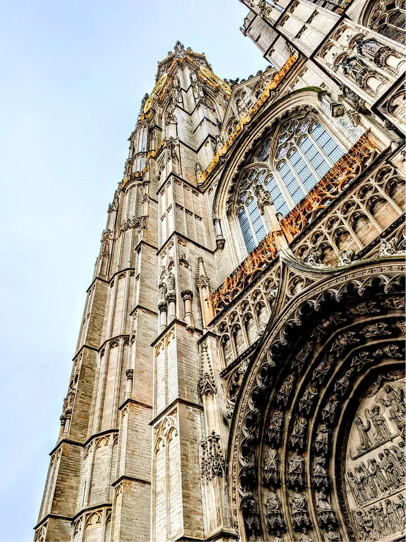 Gotische gevel en toren van de Onze-Lieve-Vrouwekathedraal in Antwerpen, schuin van onderen tegen een blauwe lucht