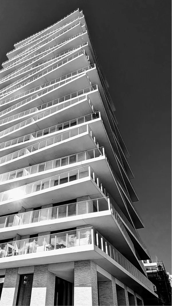 Appartementstoren met verspringende witte balkons tegen een donkere lucht, in zwart-wit