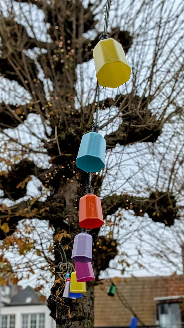 Gekleurde lampjes aan een kabel voor een kale geknotte boom in Leuven