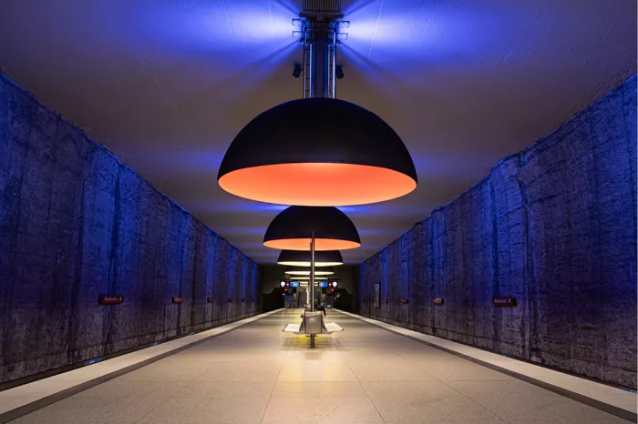 Metrostation met grote oranje gloeiende koepellampen en blauw verlichte rotswanden