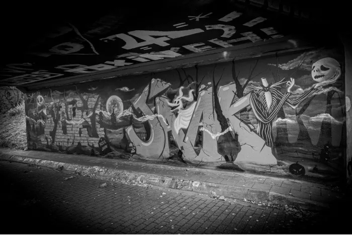 Graffitimuurschildering in een tunnel met griezelige figuren, een kerkhof en een volle maan