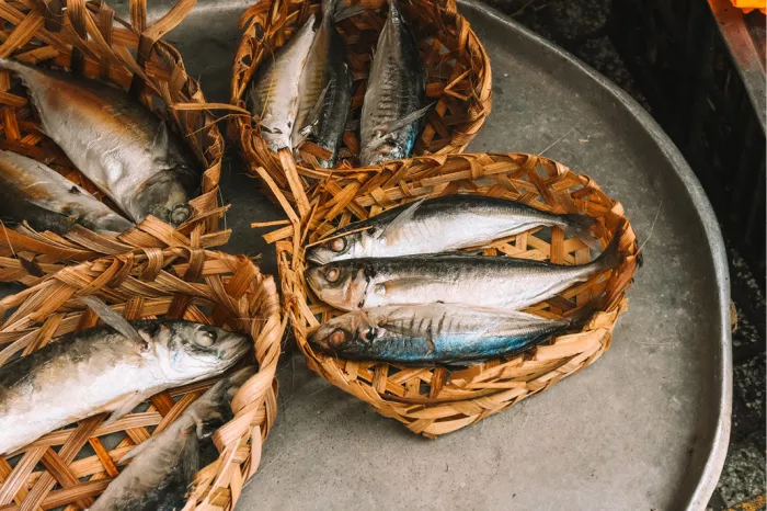 Zilveren vissen in gevlochten mandjes op een metalen schaal op een vismarkt, van bovenaf gezien