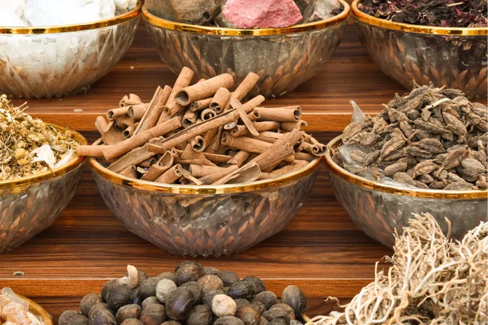 Glazen schalen met kaneelpijpjes, noten en gedroogde kruiden op een houten marktkraam