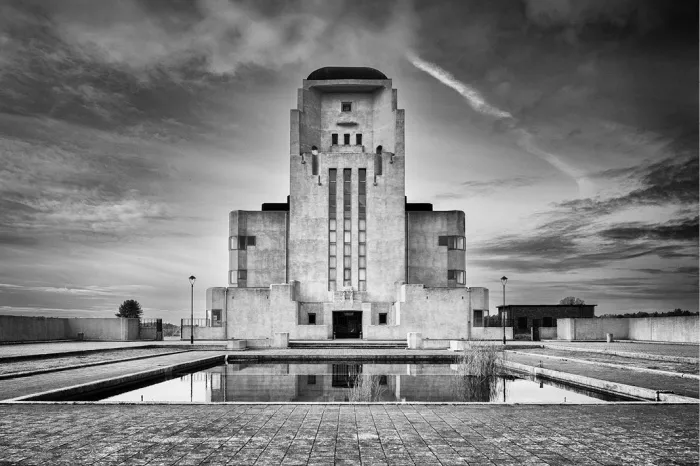 Symmetrisch art-decozendgebouw met hoge middentoren dat spiegelt in een lange vijver