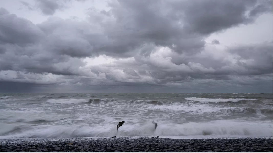 Woelige zee bij storm met paalhoofden in de golven onder donkere wolken