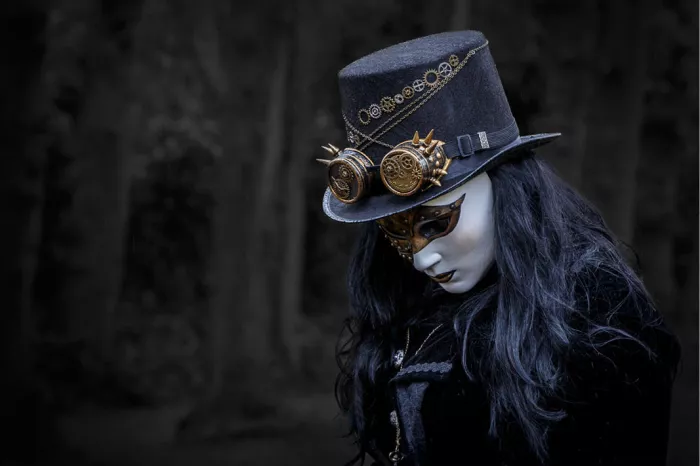 Portret van een gemaskerd meisje met steampunkhoed en koperen stofbril