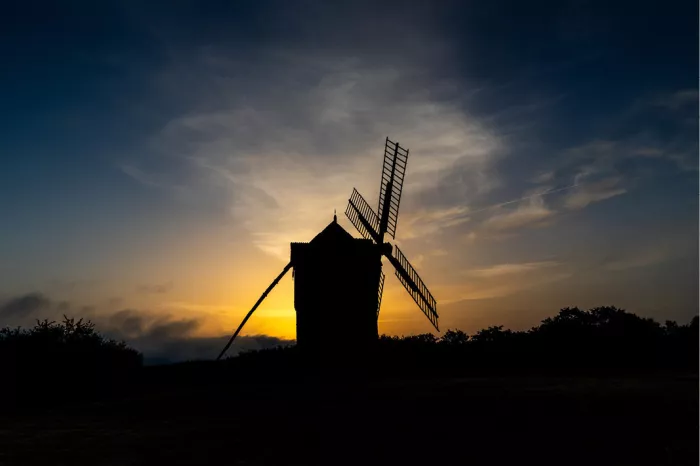 Houten windmolen als zwart silhouet tegen een lucht van diepblauw naar oranje