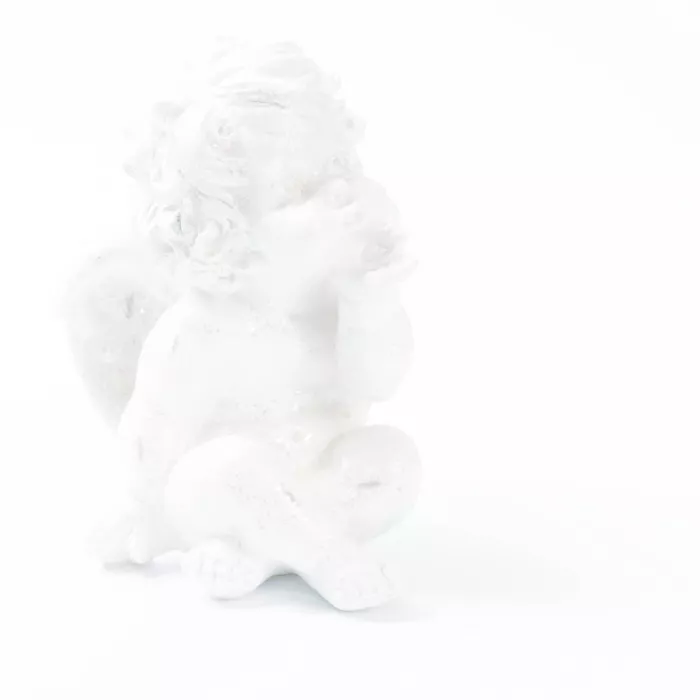De foto toont een witte engelenfiguur die in een zachte high-key belichting volledig opgaat in een bijna totaal witte achtergrond. 
